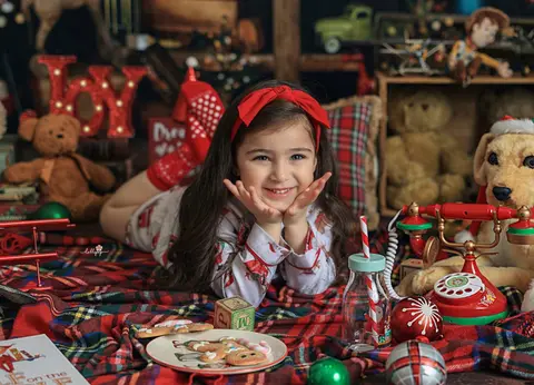 طفلة مبتسمة في ديكور شتوي بالأحمر والمربعات